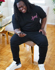 Man laughing while wearing the Wakefield District Pink Jersey Love Tee in Black. Showing unisex streetwear fit on a size 2XL.