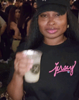 woman wearing black jersey script t-shirt with pink logo holding drink outdoors casual social setting