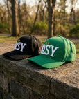 Black and green JRSY block hats placed outdoors on stone ledge
