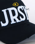 Close-up of white JRSY block embroidery on black cap