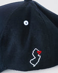 Close-up of black cap with white NJ outline and red heart embroidery