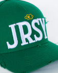 Close-up of white JRSY block embroidery on green cap
