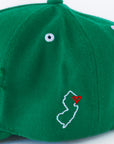 Close-up of green cap with white NJ outline and red heart embroidery
