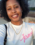 Woman wearing natural t-shirt with pink Jersey script graphic smiling outdoors