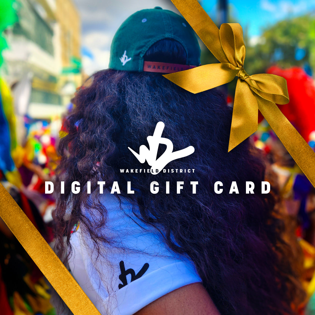 Wakefield District digital gift card graphic. Festival model in green corduroy hat is seen from behind. Centered gold text below WD logo reads 'DIGITAL GIFT CARD'. A gold gift ribbon is in the top-right corner.