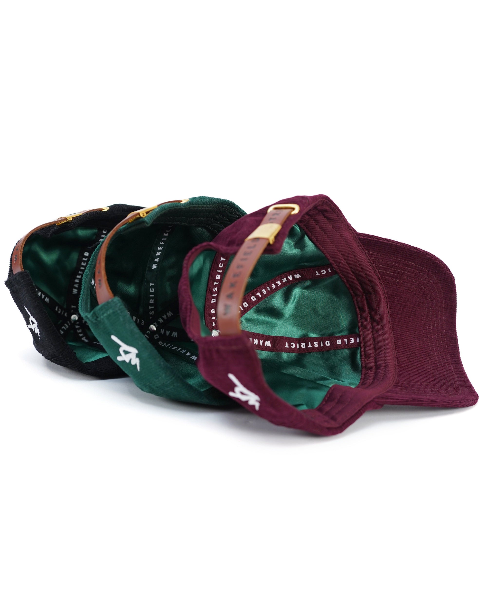 Satin lining inside view of Wakefield District Jamaica Signature Cord hats in black, Jasper green, and garnet red.