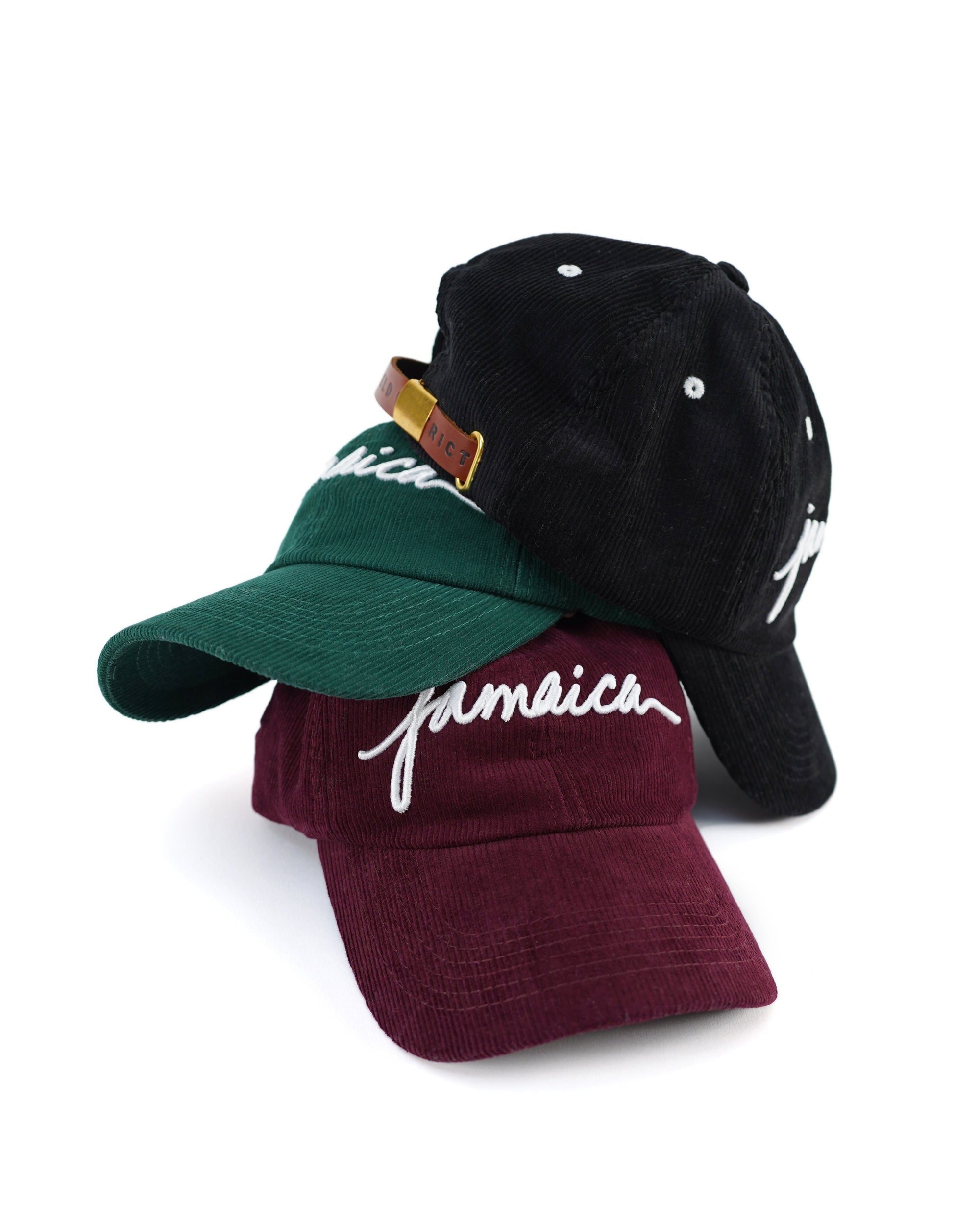 stack of Wakefield District Jamaica Signature Cord hats in black, Jasper green, and garnet red.