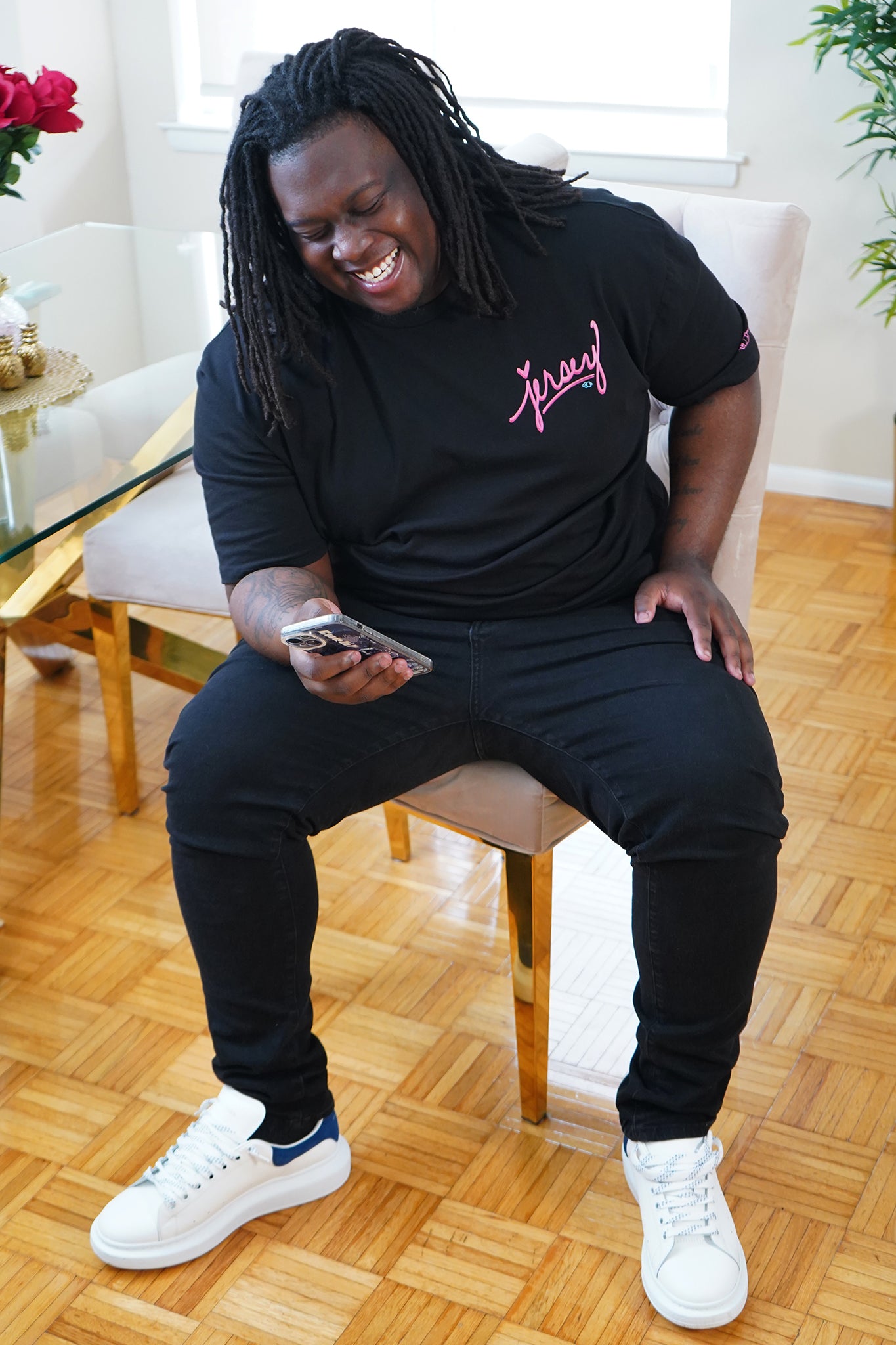 Man laughing while wearing the Wakefield District Pink Jersey Love Tee in Black. Showing unisex streetwear fit on a size 2XL.