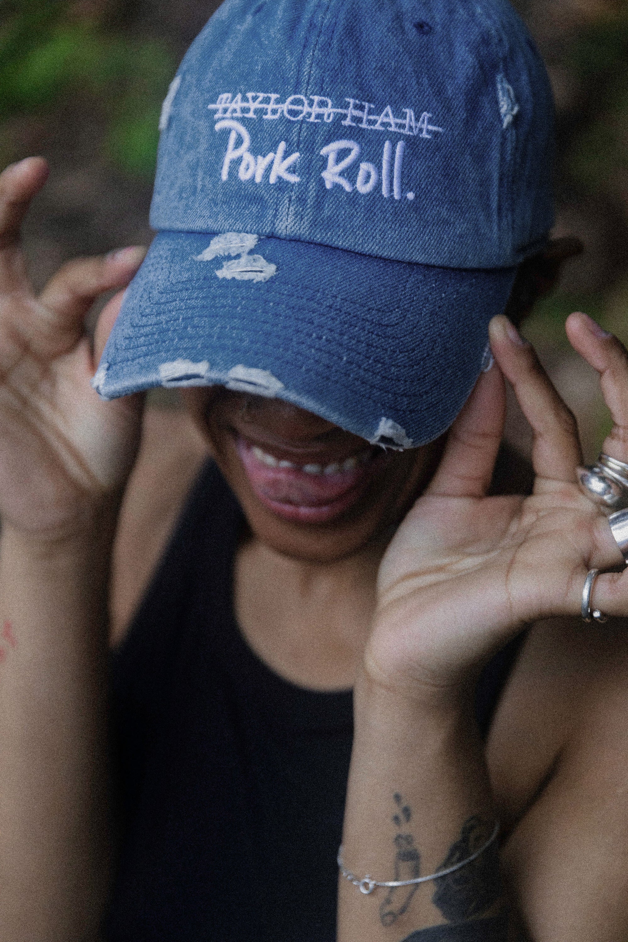 Model wearing the Denim Blue Signature Pork Roll Hat from the Contant Avenue collection by Wakefield District. Lifestyle portrait highlighting the white embroidered crossed-out Taylor Ham graphic.