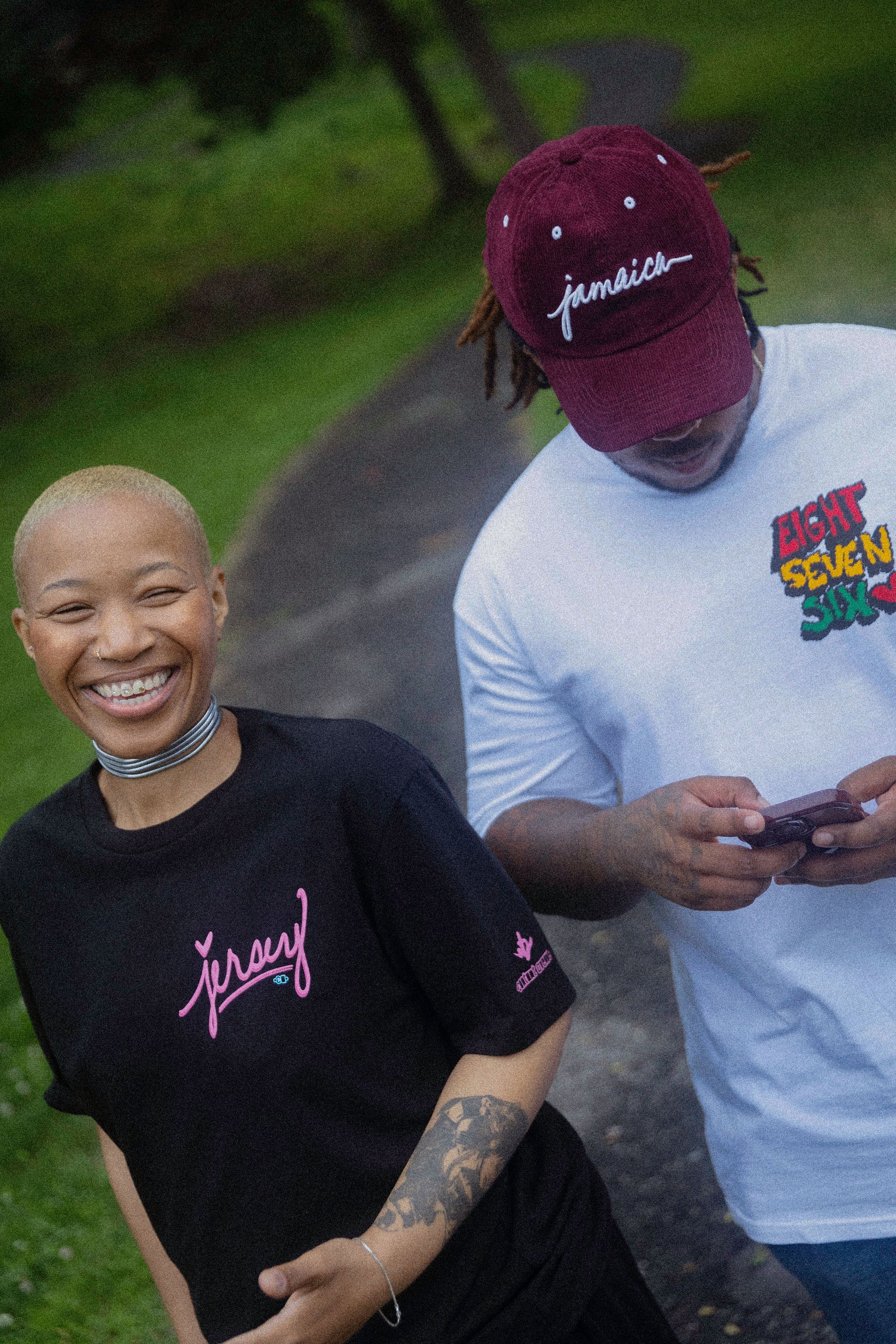 woman wearing black jersey script t-shirt with pink logo outdoors on park path casual streetwear