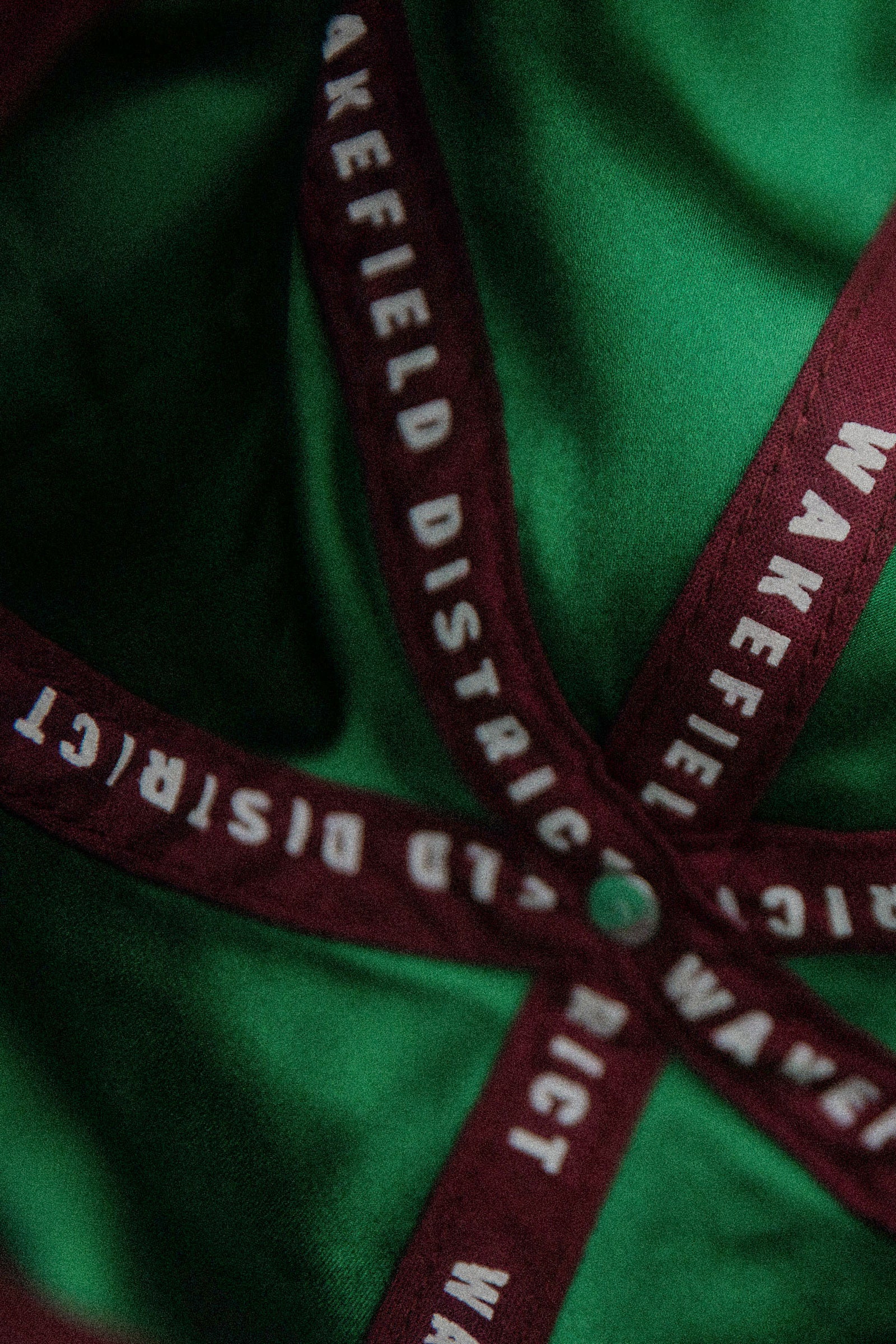 Vertical macro shot of the inside of the Jamaica Signature Cord Hat, showing the luxury emerald green satin lining and custom burgundy Wakefield District interior taping.