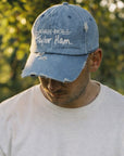 Man wearing blue denim baseball cap with Taylor Ham embroidery outdoors