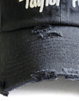 Close-up detail of the vintage distressed brim and thick white embroidery on the Black Signature Taylor Ham Hat by Wakefield District, part of the Contant Avenue collection.