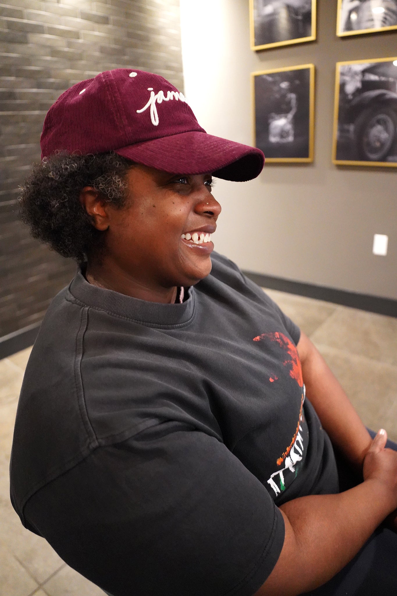 smiling woman wearing Wakefield District Jamaica Signature Cord Hat in Garnet red