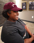 smiling woman wearing Wakefield District Jamaica Signature Cord Hat in Garnet red